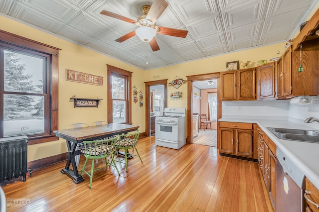 kitchen featuring gas range gas stove, light hardwood / wood-style floors, sink, ceiling fan, and dishwasher