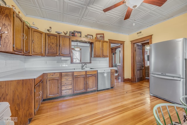 kitchen featuring sink, appliances with stainless steel finishes, ceiling fan, backsplash, and light hardwood / wood-style flooring