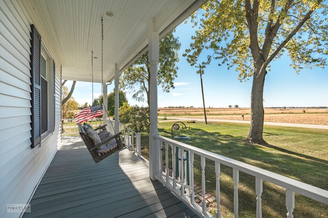 deck with covered porch, a rural view, and a lawn