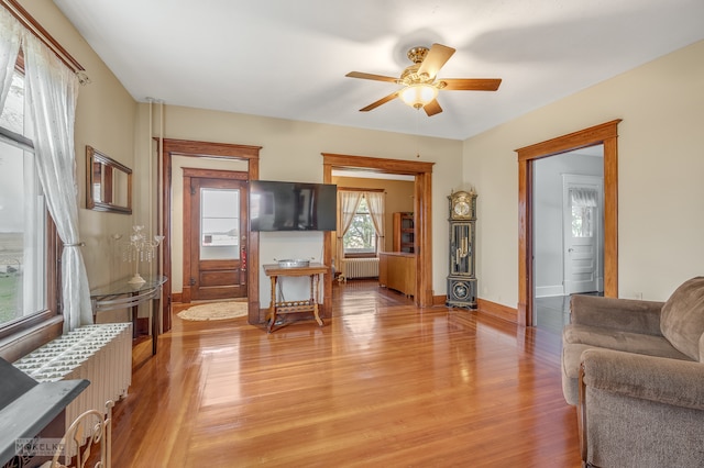 living room featuring light wood-type flooring, radiator heating unit, and ceiling fan