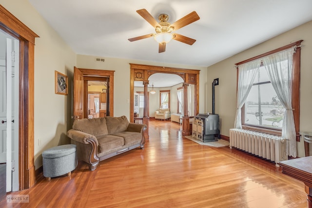 living room featuring light wood-type flooring, radiator, plenty of natural light, and a wood stove