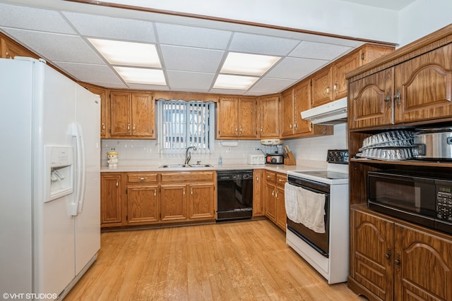 kitchen with tasteful backsplash, black appliances, sink, light wood-type flooring, and a drop ceiling