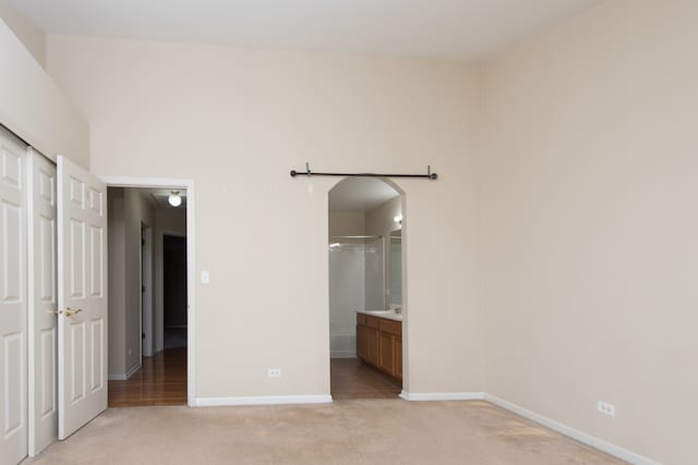 unfurnished bedroom featuring connected bathroom and light carpet