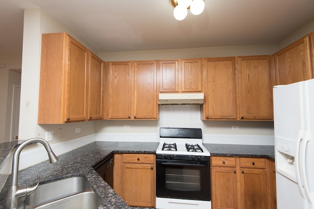 kitchen featuring sink, tasteful backsplash, white appliances, and dark stone countertops