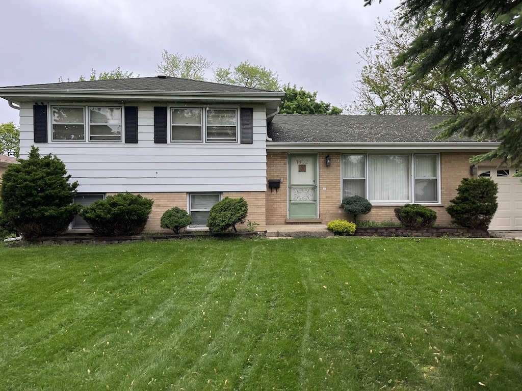 split level home with a garage and a front lawn