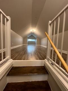 bonus room with dark wood-type flooring and lofted ceiling