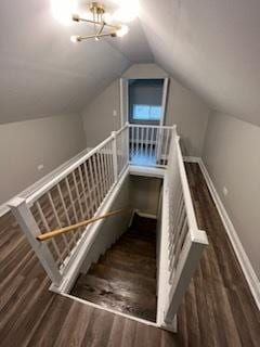 stairway with hardwood / wood-style flooring, lofted ceiling, and a notable chandelier