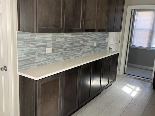 kitchen featuring light tile patterned flooring, dark brown cabinets, and decorative backsplash