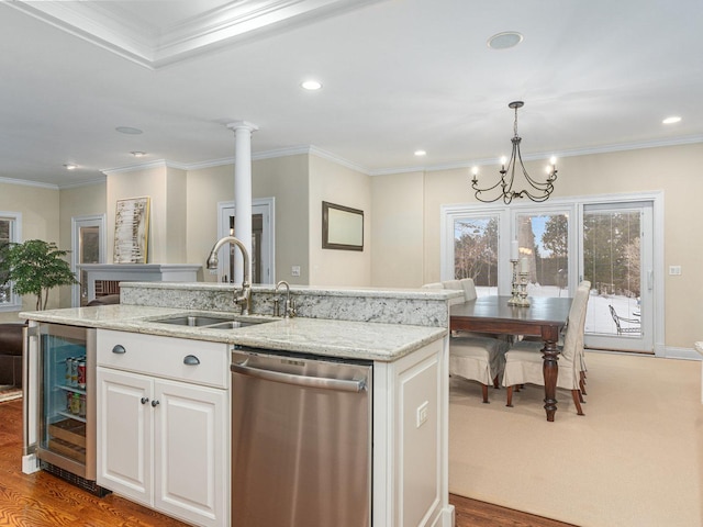 kitchen with white cabinetry, sink, hanging light fixtures, a kitchen island with sink, and stainless steel dishwasher