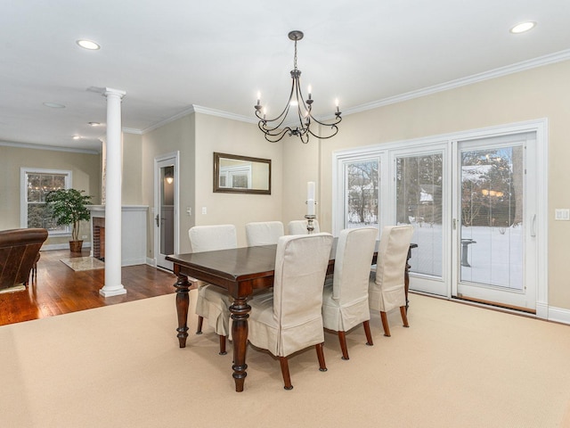 dining room featuring crown molding, wood-type flooring, an inviting chandelier, and ornate columns