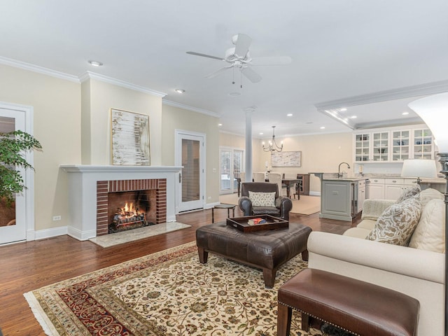 living room featuring a fireplace, wood-type flooring, ornamental molding, and sink