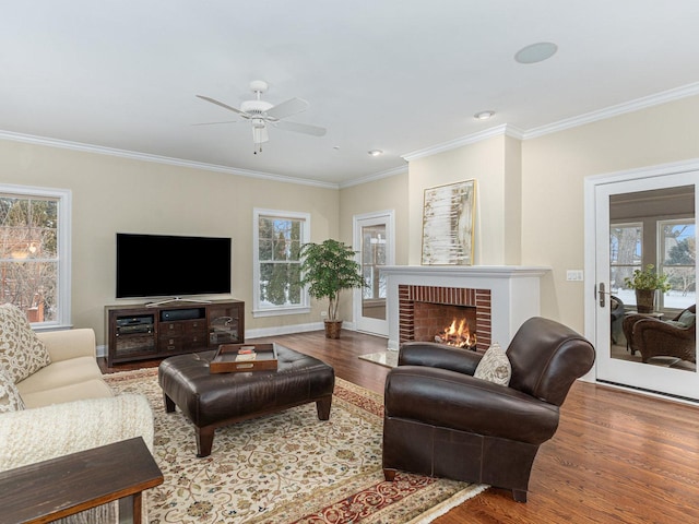 living room with hardwood / wood-style flooring, ceiling fan, ornamental molding, and a fireplace