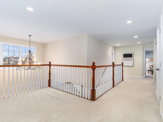 hallway featuring light carpet and an inviting chandelier