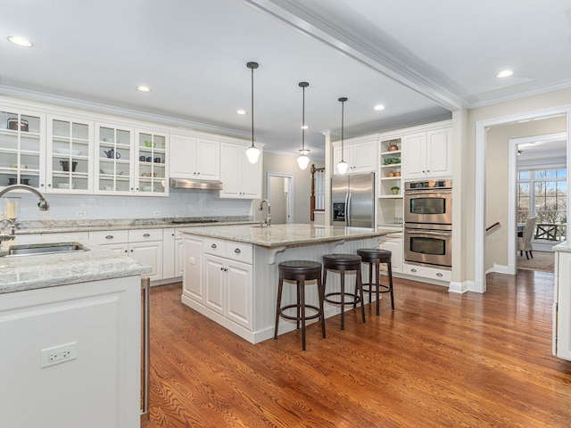 kitchen featuring white cabinetry, sink, stainless steel appliances, and a center island with sink