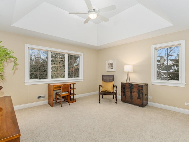 sitting room with a raised ceiling, light carpet, and ceiling fan