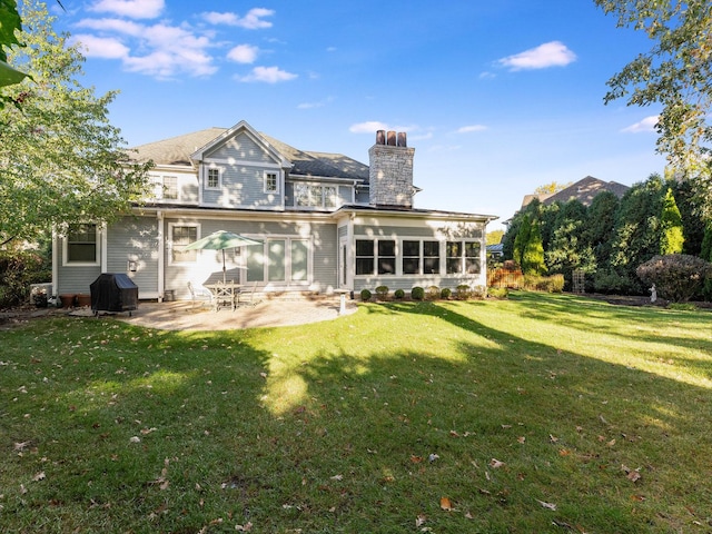 rear view of house with a yard, a patio area, and a sunroom