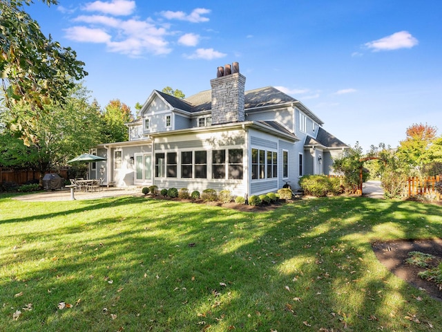 rear view of house featuring a patio, a yard, and a sunroom