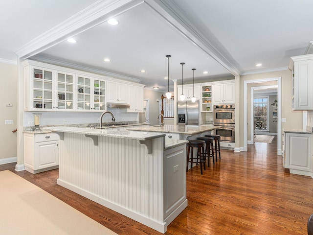 kitchen featuring white cabinets, appliances with stainless steel finishes, and a large island with sink