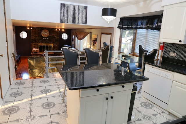 kitchen featuring a fireplace, hanging light fixtures, light hardwood / wood-style flooring, a kitchen island, and dishwasher