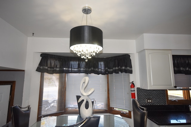 interior space featuring tasteful backsplash, white cabinetry, a notable chandelier, and plenty of natural light