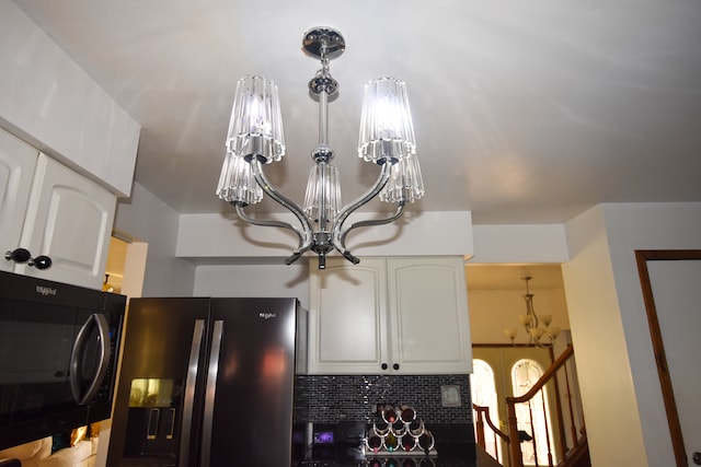 interior details featuring white cabinets, a notable chandelier, and stainless steel fridge