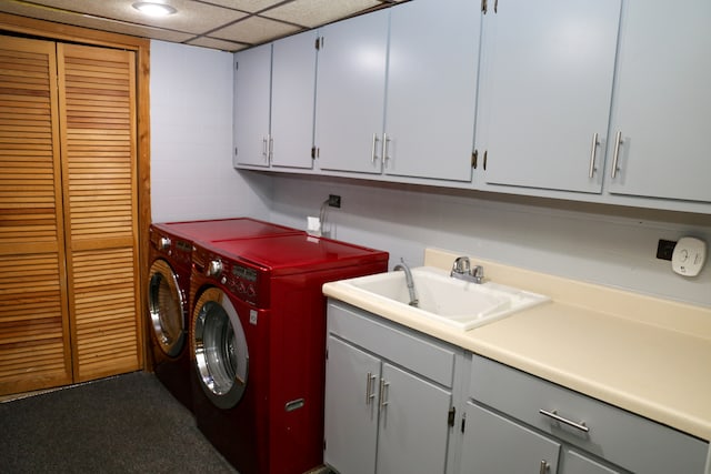 clothes washing area with washing machine and dryer, cabinets, and sink