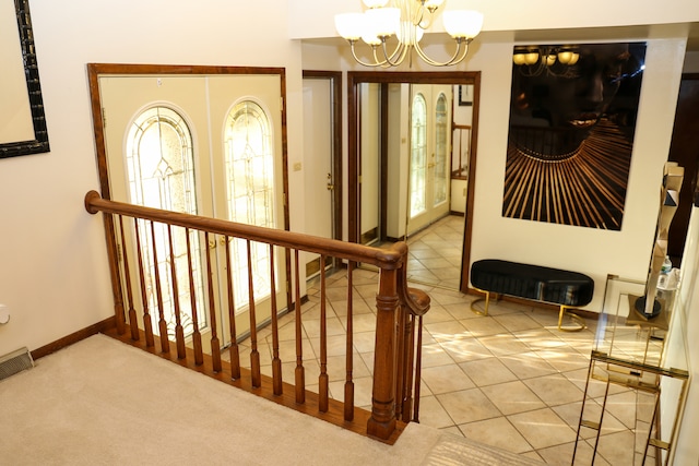 stairs with french doors, tile patterned flooring, and a notable chandelier