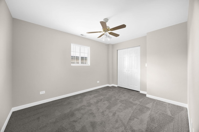 empty room with ceiling fan and dark colored carpet