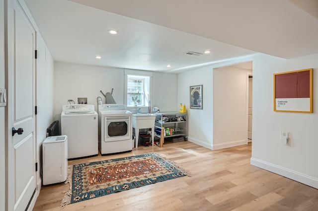 laundry area featuring washing machine and clothes dryer and light wood-type flooring