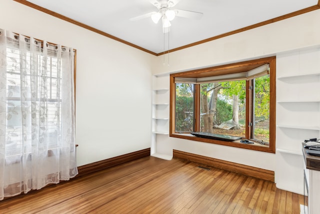 empty room with ornamental molding, wood-type flooring, and ceiling fan