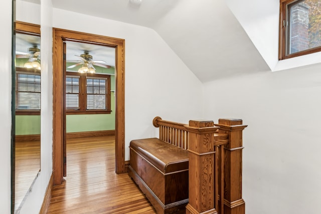 hallway with vaulted ceiling with skylight and light wood-type flooring