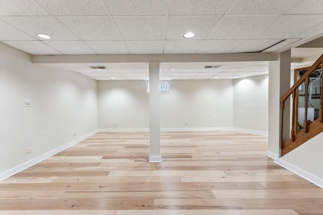 basement with a drop ceiling and light wood-type flooring