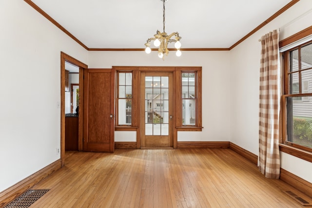 empty room featuring light hardwood / wood-style floors, ornamental molding, and a chandelier