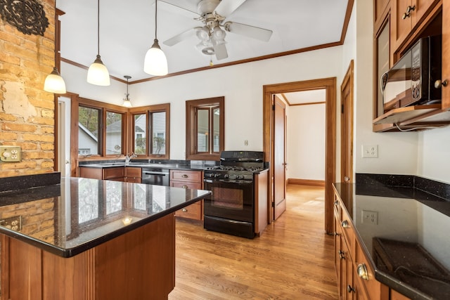 kitchen with crown molding, decorative light fixtures, black appliances, and light wood-type flooring