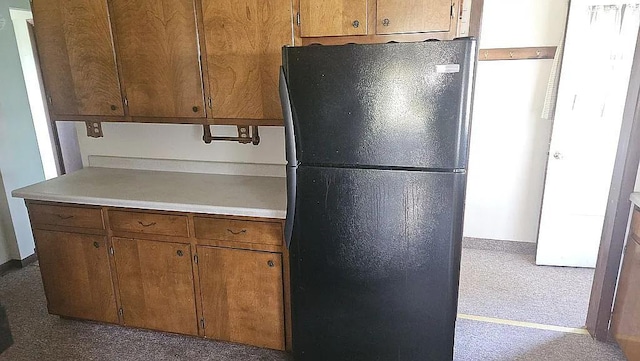 kitchen featuring light colored carpet and black refrigerator