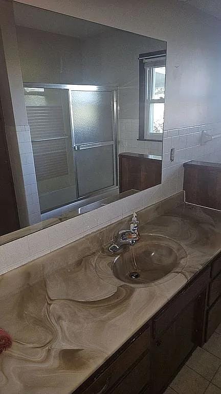 bathroom featuring vanity, tile patterned flooring, and a shower with door