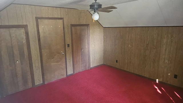 additional living space with ceiling fan, vaulted ceiling, and wooden walls