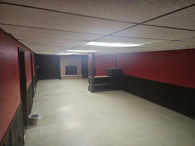 basement with a brick fireplace and a paneled ceiling