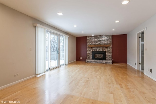 unfurnished living room with light wood-type flooring and a brick fireplace