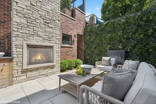 view of patio / terrace featuring an outdoor living space with a fireplace and a balcony