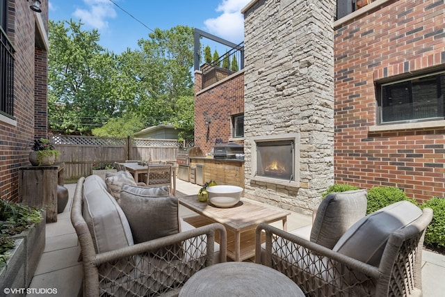 view of patio / terrace featuring exterior kitchen, grilling area, an outdoor living space with a fireplace, and a balcony