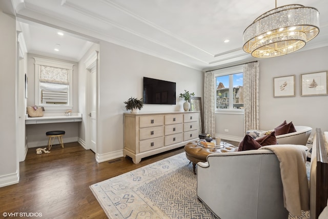 living room featuring an inviting chandelier, ornamental molding, built in desk, and dark hardwood / wood-style flooring