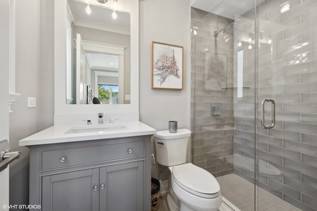 bathroom featuring a shower with door, vanity, crown molding, and toilet