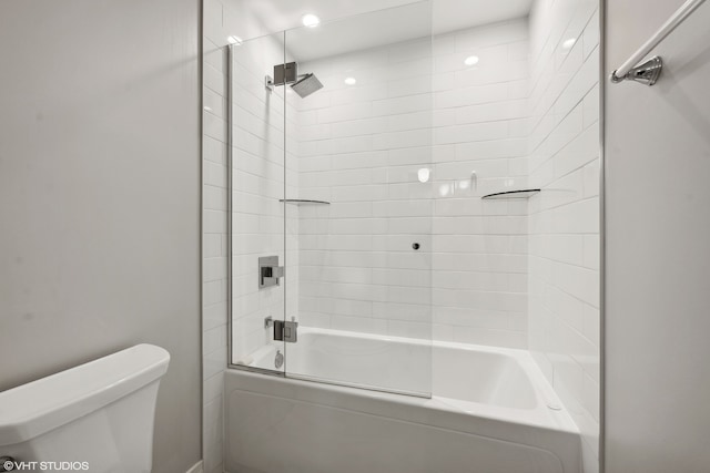 bathroom featuring toilet and combined bath / shower with glass door