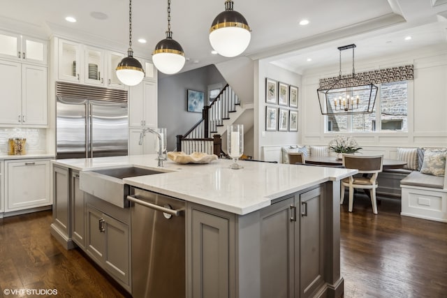 kitchen featuring light stone countertops, a kitchen island with sink, white cabinets, and stainless steel appliances