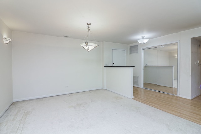 empty room with wood finished floors, visible vents, and baseboards