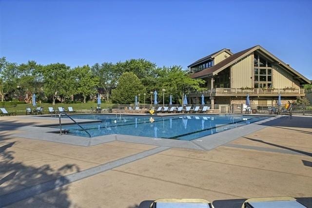 community pool with a patio area and fence