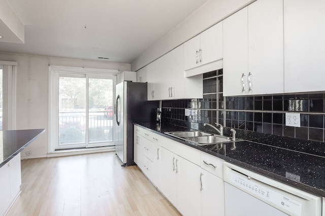 kitchen featuring white dishwasher, a sink, white cabinetry, backsplash, and light wood finished floors