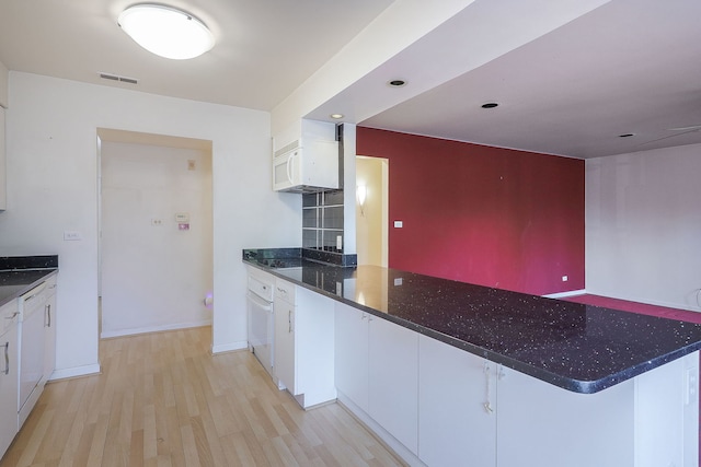 kitchen with dark stone countertops, light wood-type flooring, visible vents, and white cabinets