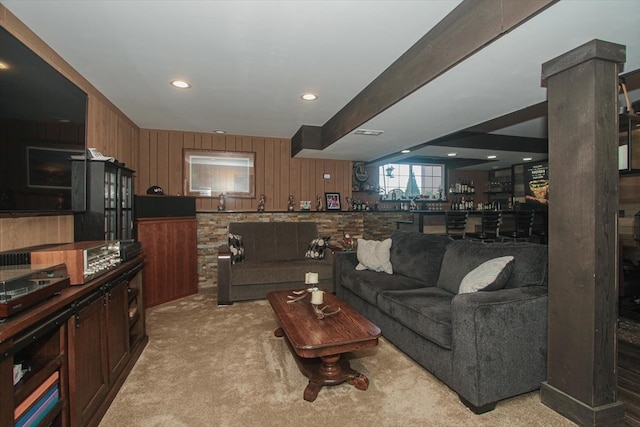 living room with light carpet, indoor bar, and wood walls